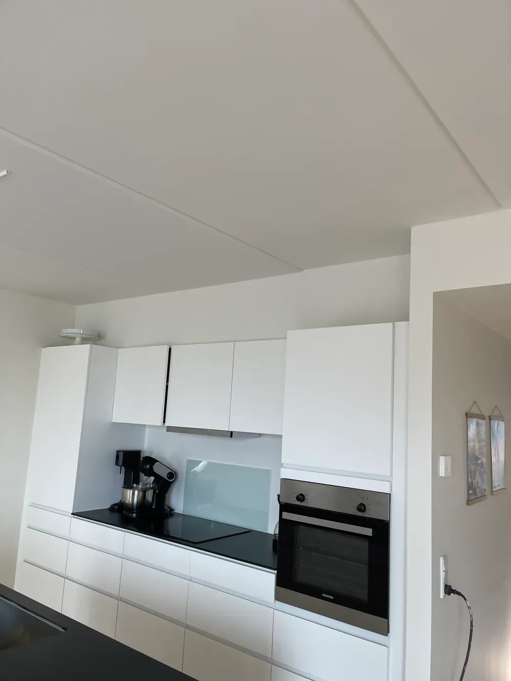 Hvidt køkken med indbygget ovn og sort bordplade – Maler Microcement, Herlev og omegn