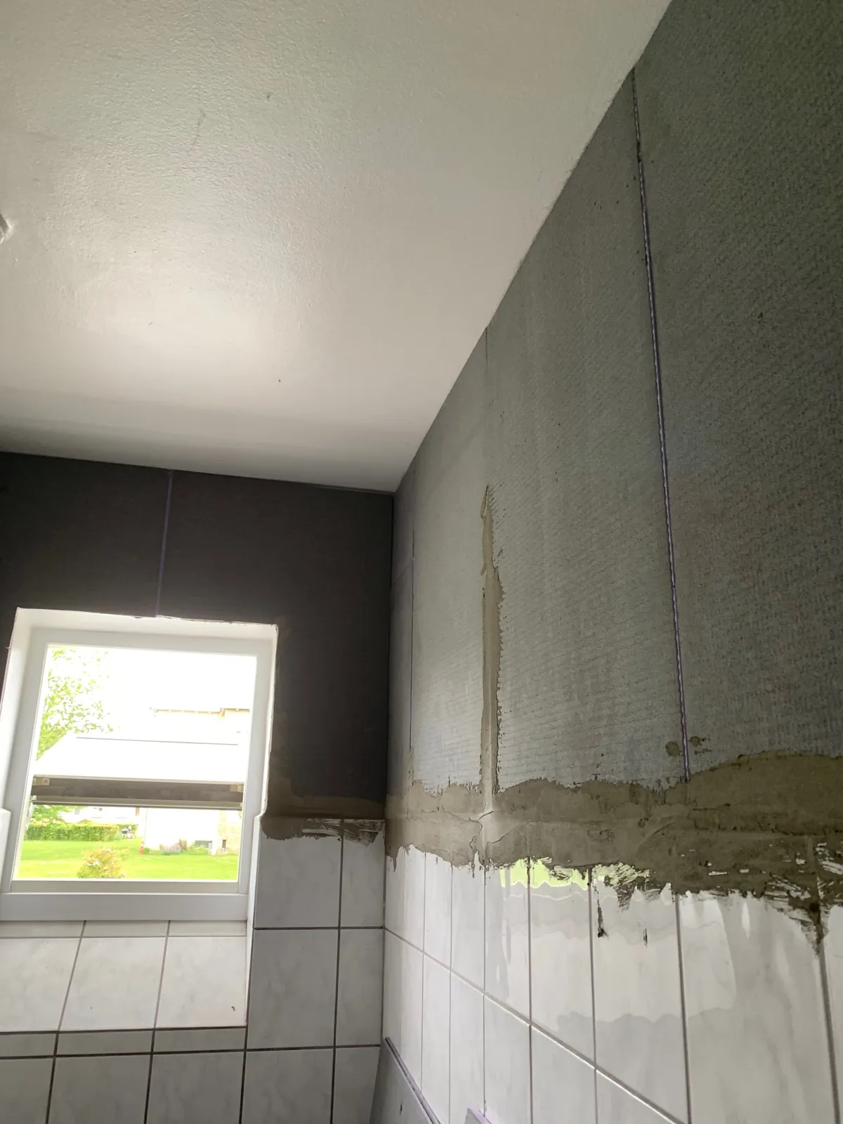 Væg med grå overflade over fliser under arbejde – Maler Microcement, Herlev og omegn
